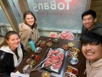 Four people smiling and enjoying dessert at a restaurant table labeled 