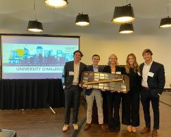 A group of people holding an award, projected screen in background.