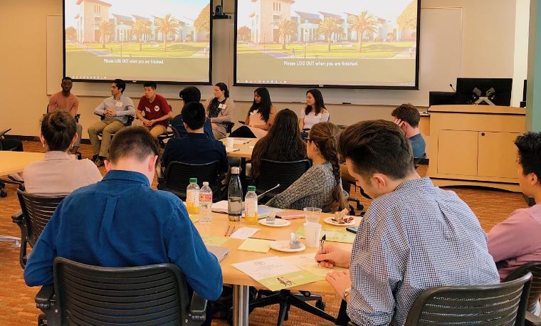 People attending a Career Startup Leadership Event, sitting around tables, looking at screens.