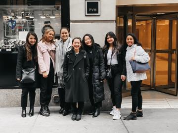 A group of eight people posing together on an urban street.
