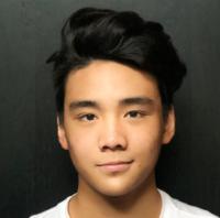 A person wearing a white shirt against a dark background.