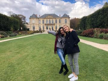 Two people posing in front of a chateau garden.