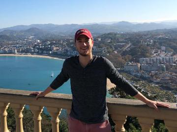Person posing in front of a scenic coastal city view.