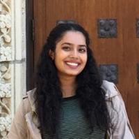 A person standing in front of an ornate wooden door.