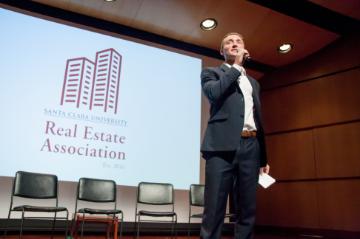 Man speaking on stage at Real Estate Association Event 2017.