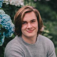 A person sitting on grass near blue hydrangeas.