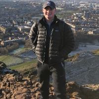 A person standing on a mountain overlooking a town.