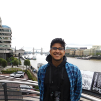 Alt text: Person smiling in front of a river and modern buildings.
