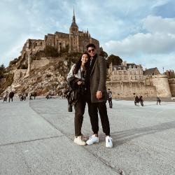 Two people stand in front of a historic building.