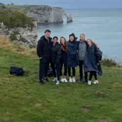 A group of people standing on a cliffside overlooking the ocean.