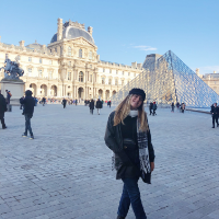 A person posing outside the Louvre Museum in Paris.