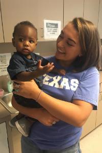 A woman holding a baby in a kitchen.