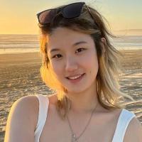 Person smiling on a beach at sunset.