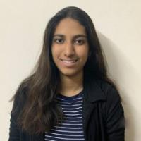 A person smiling while wearing a striped top and black jacket.