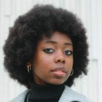 A person wearing a gray coat and black turtleneck.