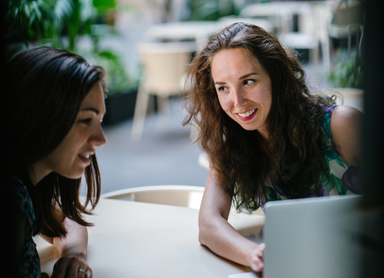 Two women talking with a laptop image link to story