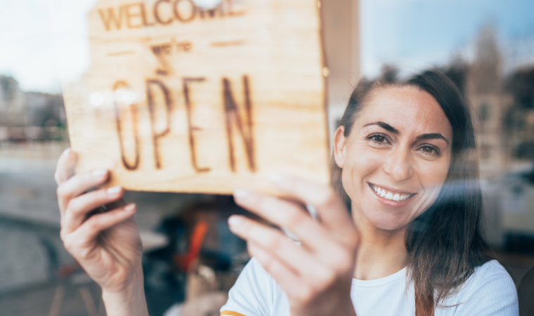 Photo of woman in a shop in front of an open sign.