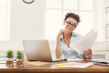 Photo of woman at computer reviewing a paper 