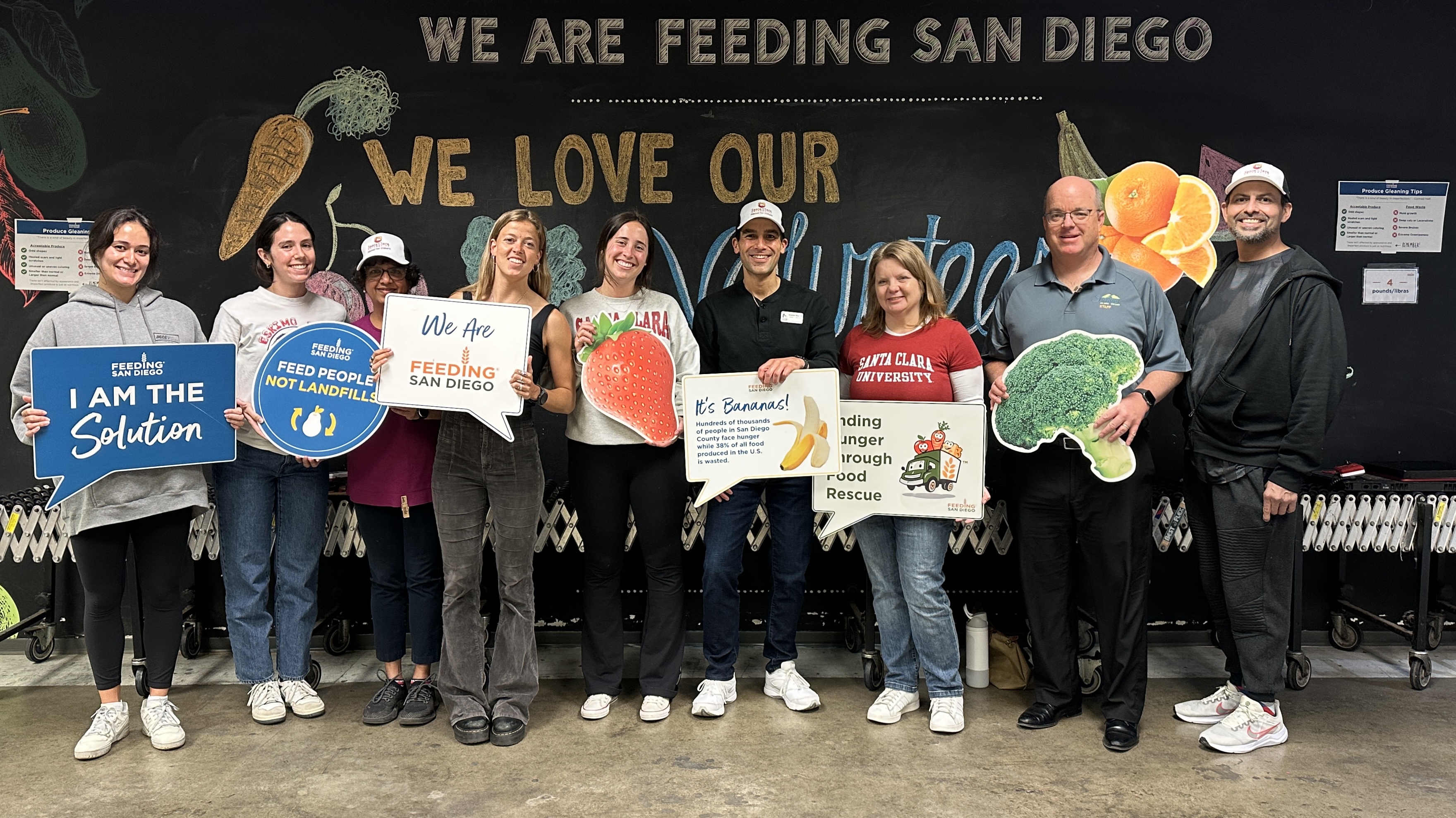 Alumni posing with their signs