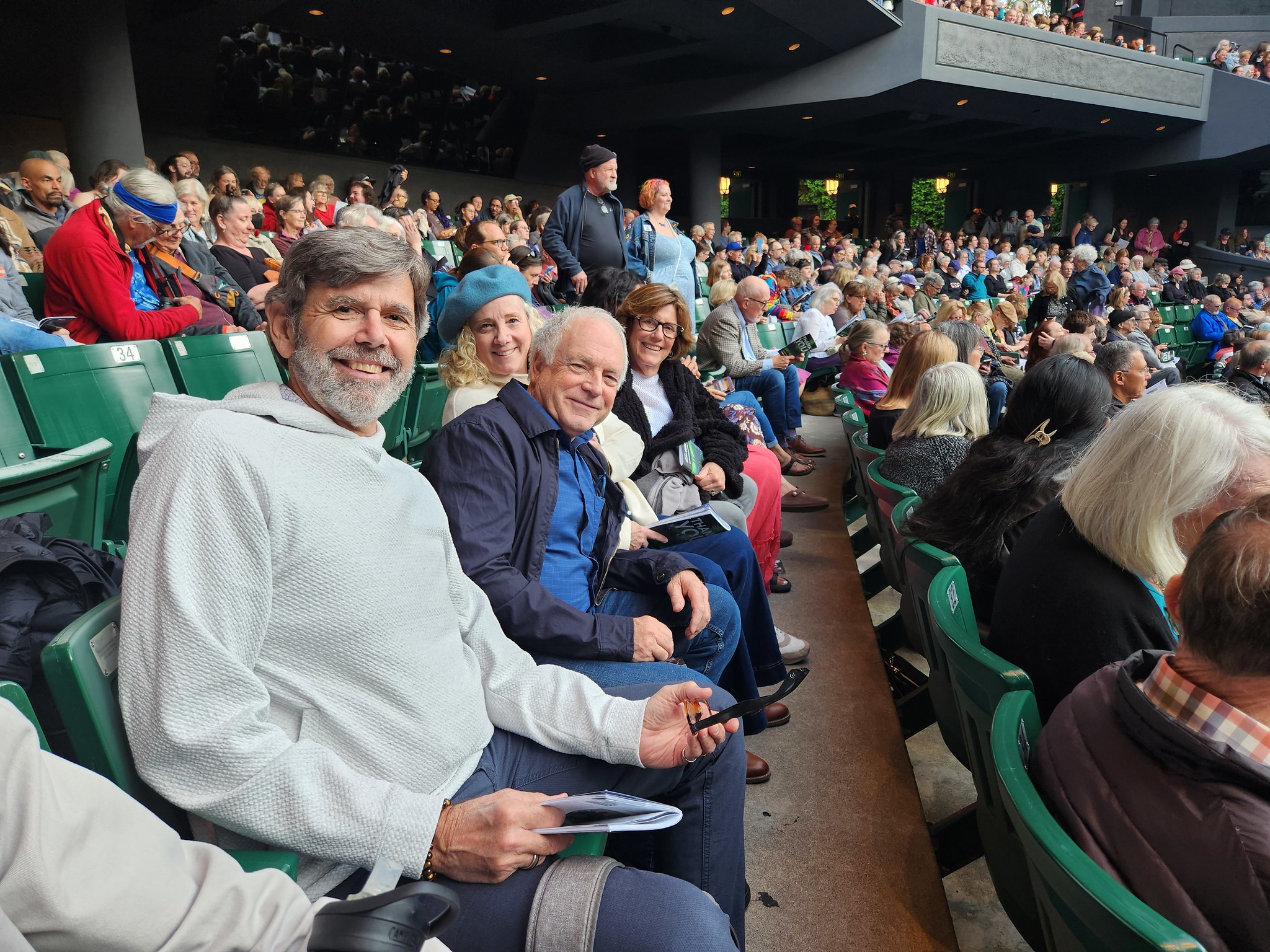 A group of smiling people sitting in stadium-style seats at the Ashland Shakespeare Festival. 