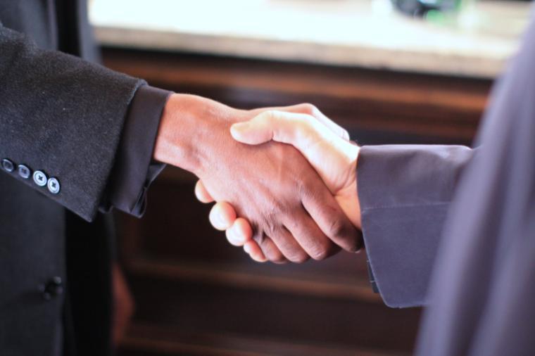 Two people in suits shaking hands.