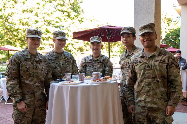 Five people in military uniforms around a table, titled 