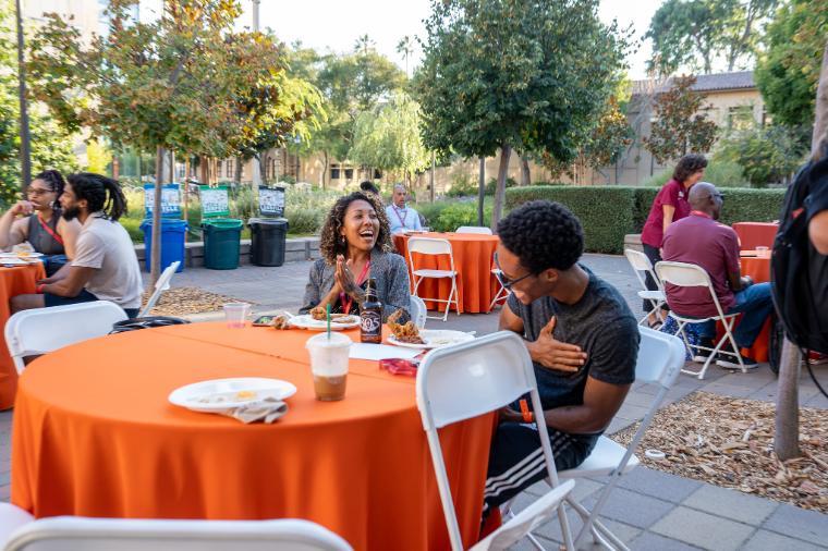 People sitting at tables outdoors at the Black Alumni event 2022.