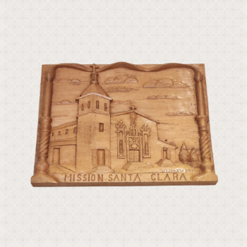 A wooden plaque, on which is carved an image of Mission Santa Clara de Asís, under which is inscribed 