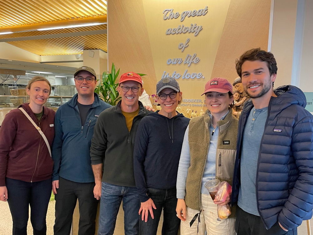 A group of smiling people in front of a sign that says The great activity of our life is to love.