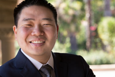 A person smiling in an outdoor setting.