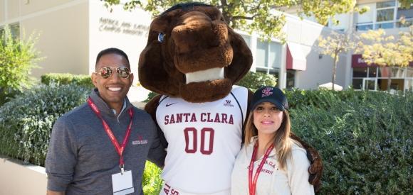 Two alumni standing with Bucky Bronco.