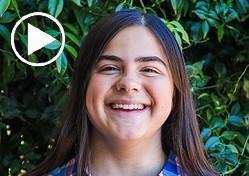 Girl with long dark hair smiling.
