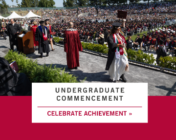 Student in a white dress crossing the graduation stage.