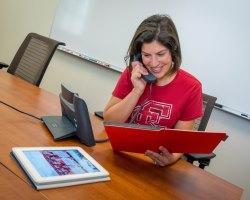 Woman wearing SCU t-shirt making a phone call.
