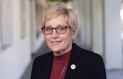 Portrait of woman in a burgundy blouse and dark blazer.