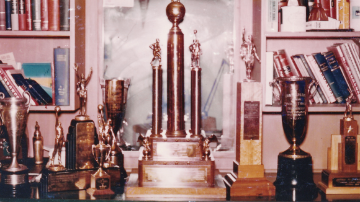 A vintage photo from c.1957 of several USF sports trophies on a bookshelf 