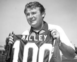 Black and white photo of Pat Malley holding jersey number 100.