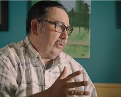 Man wearing a plaid shirt speaking.