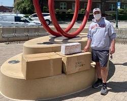 Man in a SCU sweatshirt standing next to shipping boxes.