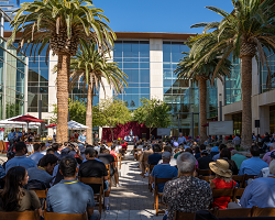 Seated crowd outside a large academic building.