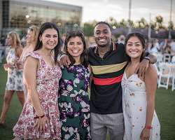 Four individuals standing with arms around one another.