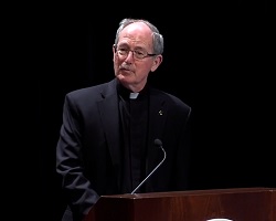 University President Fr. Michael Engh speaking at podium.