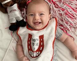 Smiling baby in a Born to be a Bronco bib.