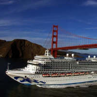 A large cruise ship sailing in front of San Francisco's Golden Gate Bridge.