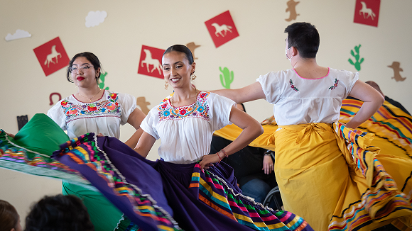 Women in traditional Folklorico costumes dancing.