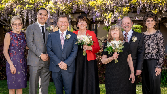 A group of smiling people in formalwear standing in SCU's Mission Gardens.