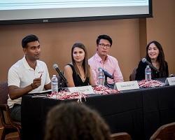 Four young alumni panelists sitting behind a table.