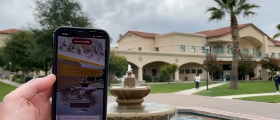A person holding up a phone with a historical rendering on the screen.