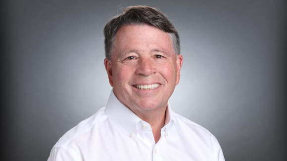 A smiling man in a white, collared shirt.
