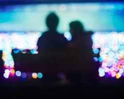 Silhouette of two people sitting on a bench.